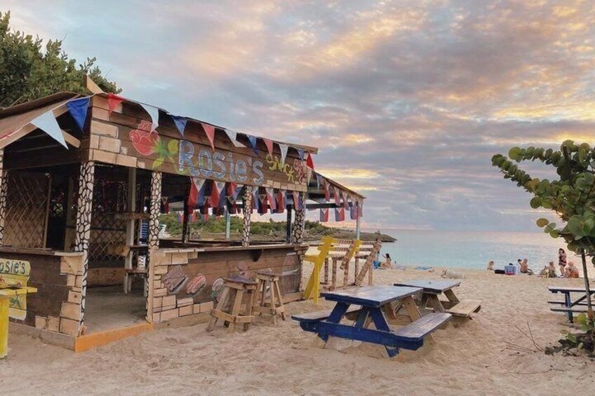 A beachside restaurant named 'Rosie's' with a wooden structure, tables, and a view of the ocean. 2