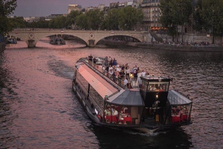 A riverboat with passengers, a bridge, and buildings in the background. 3