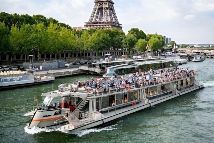 A river cruise boat with passengers, docked near the Eiffel Tower. 1