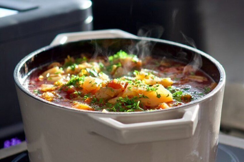 A pot of stew with steam rising, garnished with herbs, and a blurred background. 2