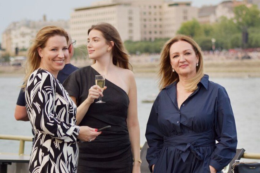 Three people standing by a waterfront with buildings in the background. 5
