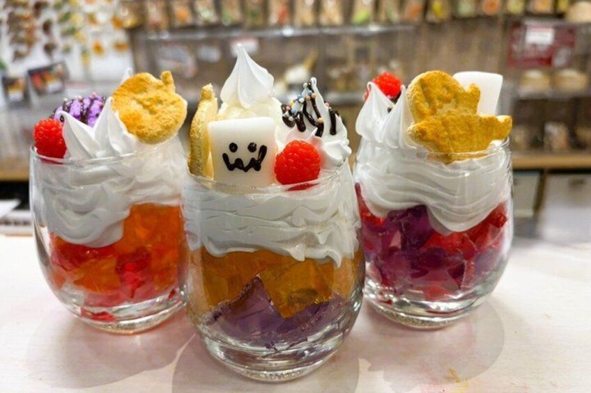 Three layered desserts in clear glasses with whipped cream and fruit toppings. 3