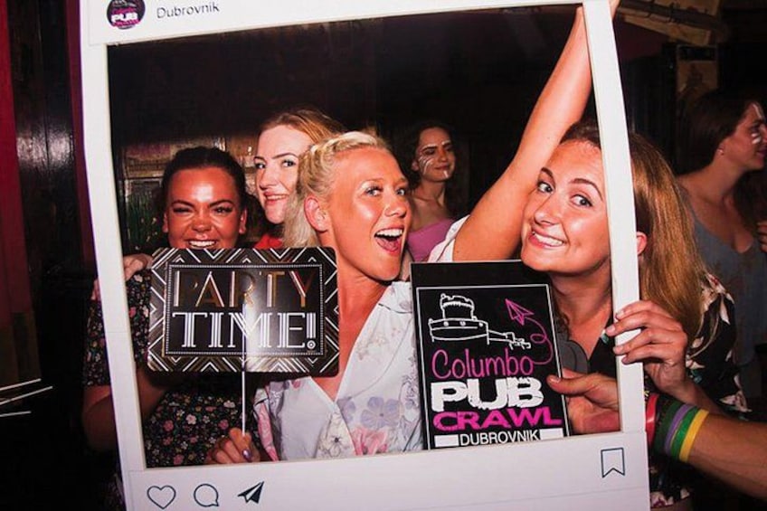 A group of people at a party with a sign that reads 'Columbo Pub Crawl.' 1