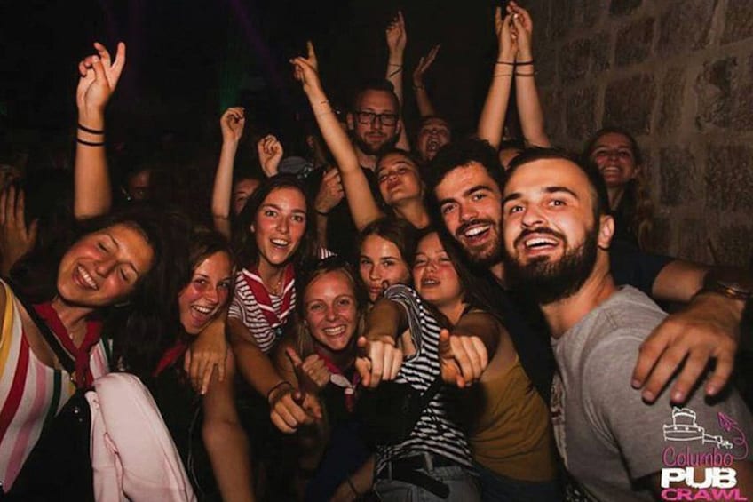 A group of people at a social gathering, some raising their hands. 5