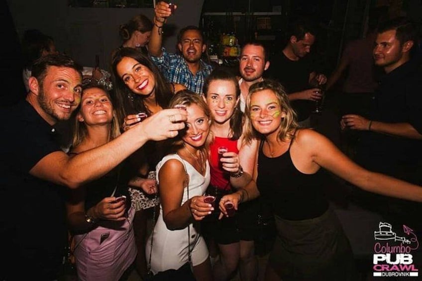 A group of people at a social gathering, possibly a party or event, with drinks in hand. 4