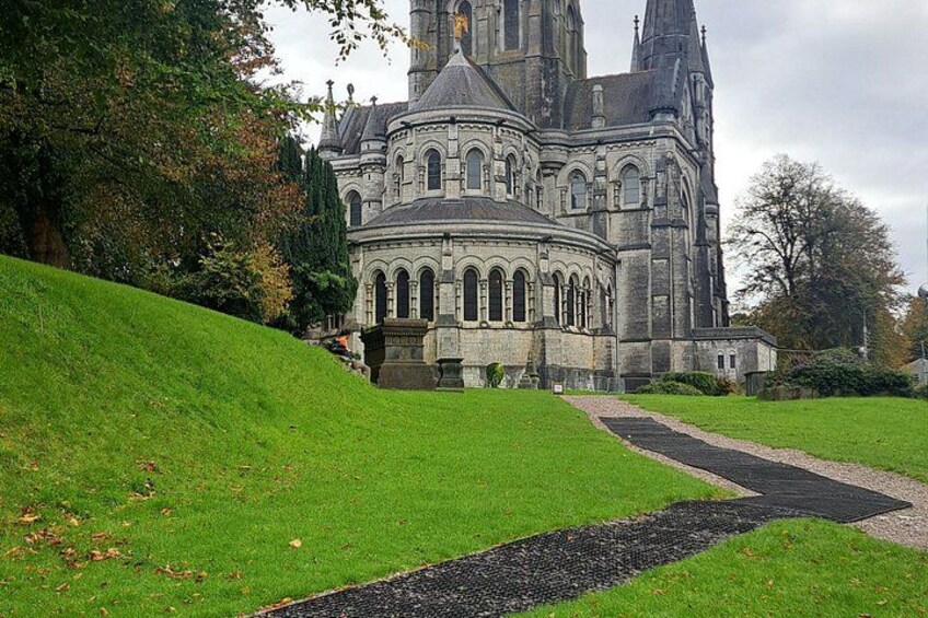 A large historic building with a dome and towers, surrounded by a well-maintained lawn and a gravel path. 3