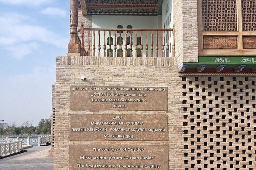 A building with a plaque in a foreign language, a balcony with a railing, and a patterned wall. 3