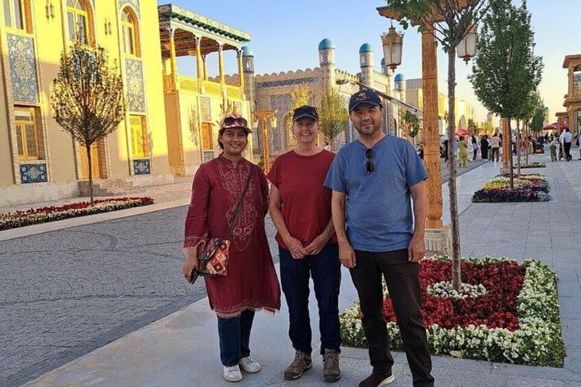 Three people standing in front of a building with intricate architecture and a flower bed. 4