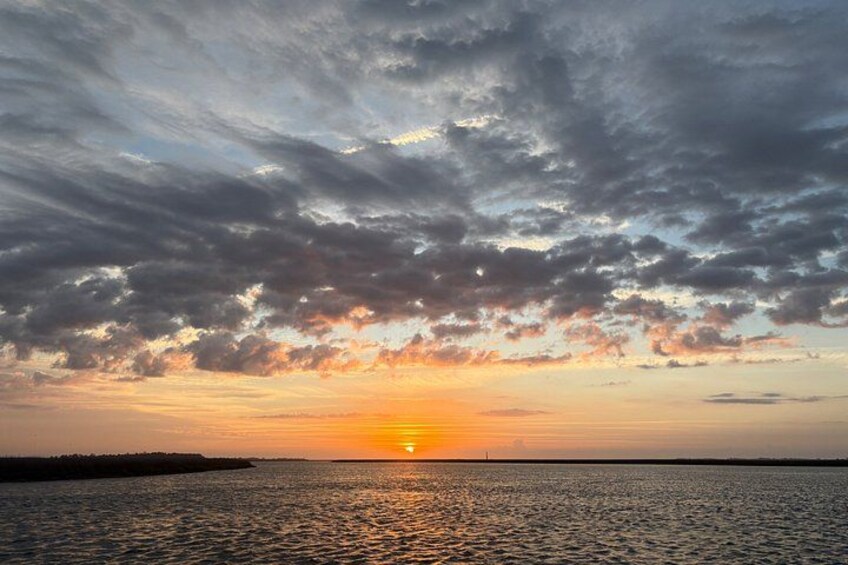 A sunset over a body of water with clouds in the sky. 1