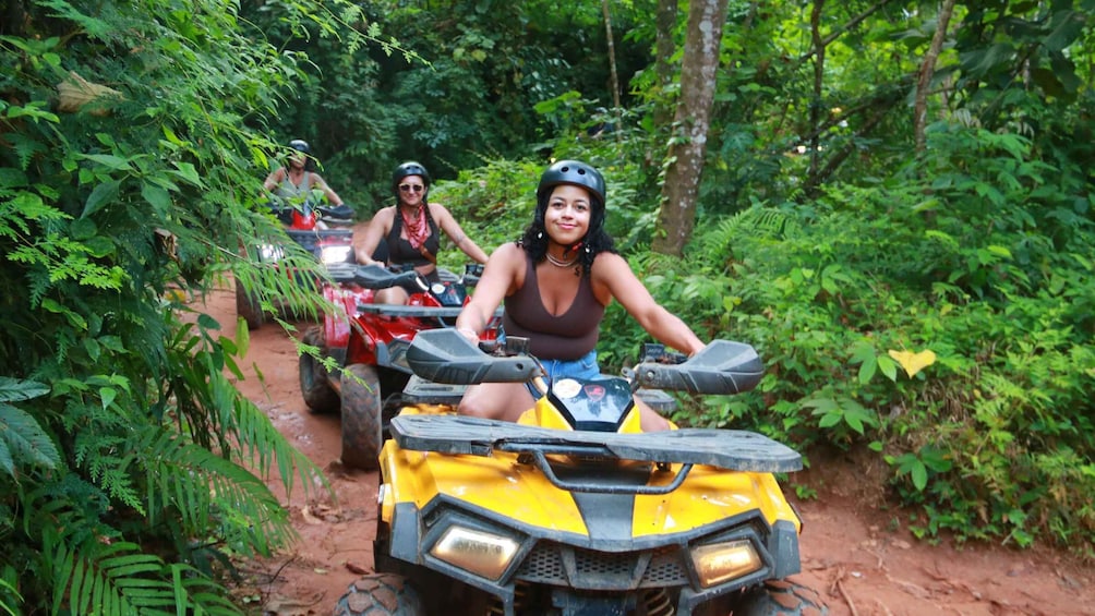 Two people on yellow off-road vehicles in a forested area. 1