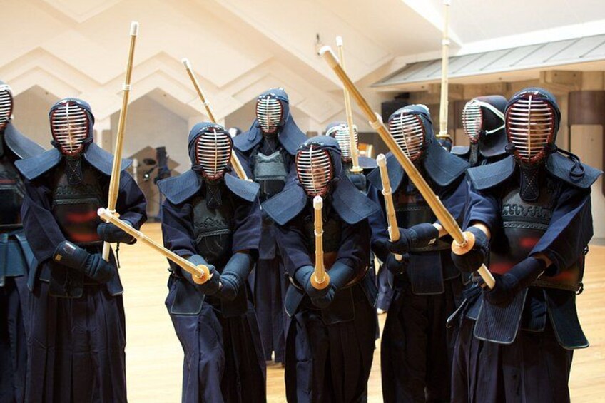A group of individuals in traditional martial arts attire holding wooden staffs. 2