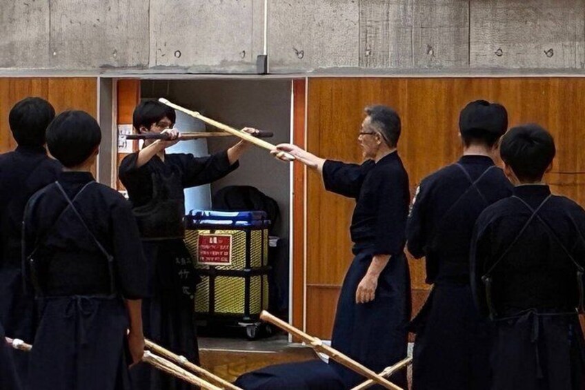 A group of people in traditional attire practicing martial arts with wooden sticks. 1
