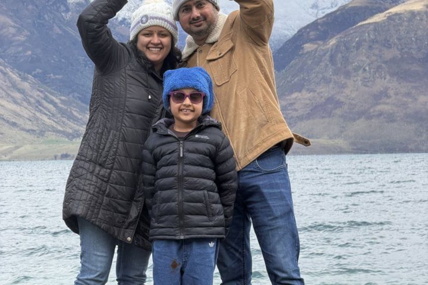 A family of three by a lake with mountains in the background. 4