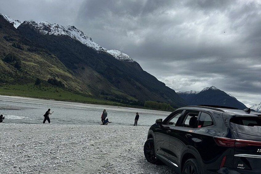 A group of people near a lake with mountains in the background. 2