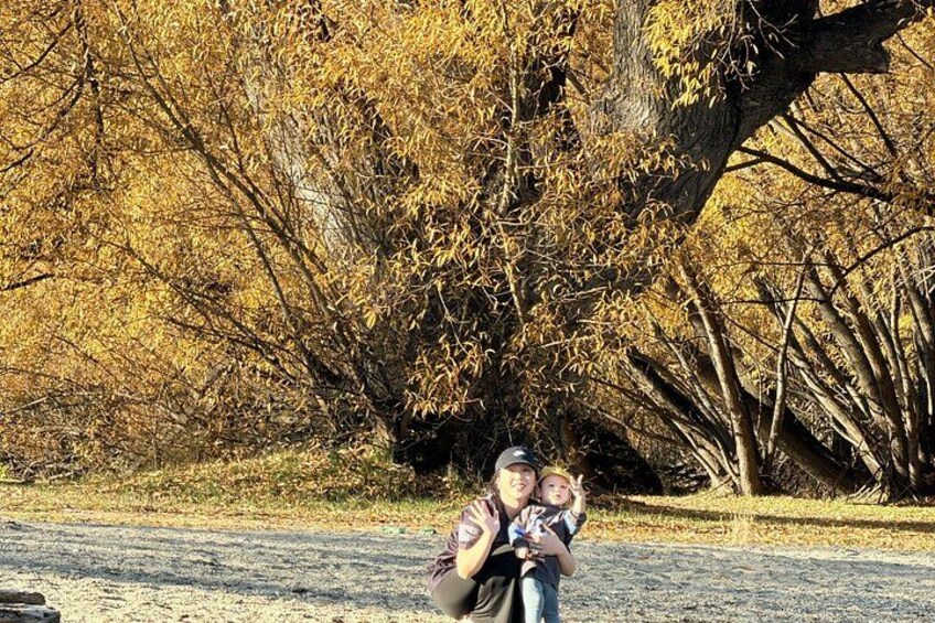 A person holding a child in a park with autumn-colored trees. 5