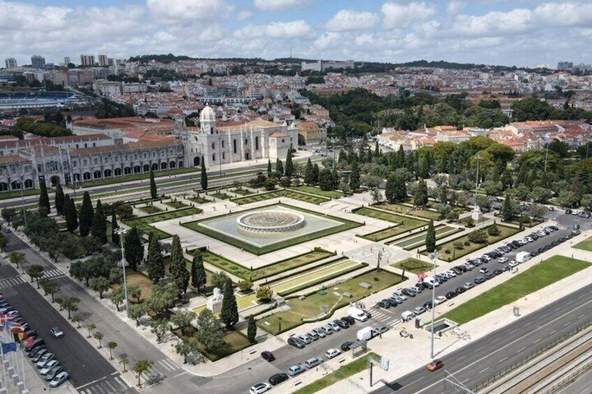 A cityscape with a prominent historical building, a well-maintained garden, and a busy road. 4