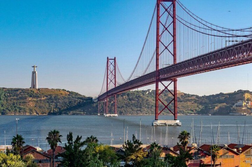 A large red bridge spanning a body of water, with a hill and a tower in the background. 3