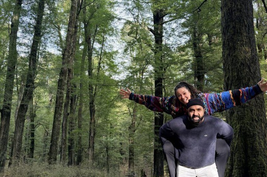 Two people in a forest with tall trees and dense foliage. 4