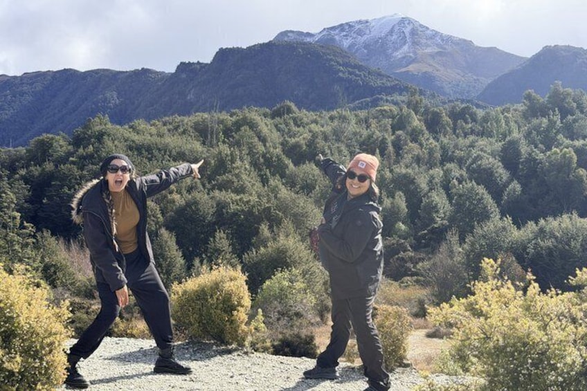 Two people dancing on a gravel path with a mountainous landscape in the background. 5