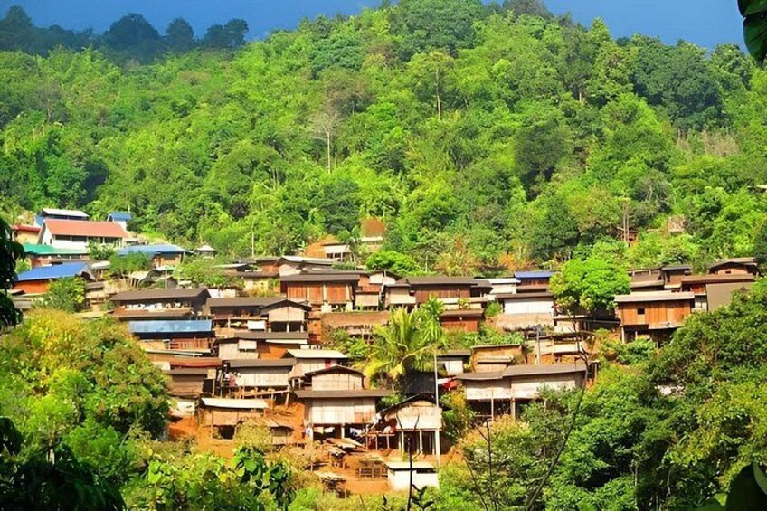 A hillside village with traditional houses, dense greenery, and a clear sky. 3