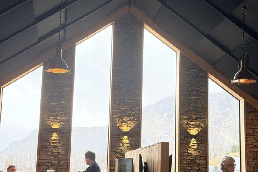 A restaurant with large windows, stone pillars, and hanging pendant lights. 1