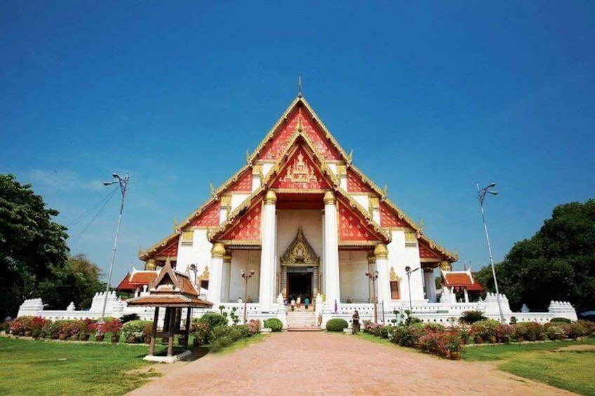 A temple with a red and white facade, a central entrance, and a surrounding garden. 3