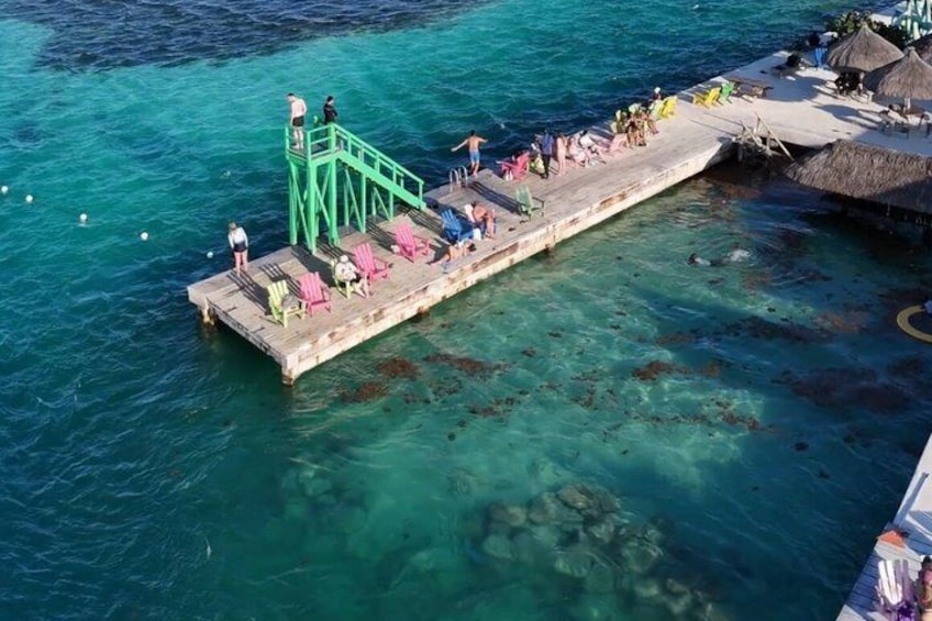 A pier with people, chairs, and a thatched-roof structure. 2