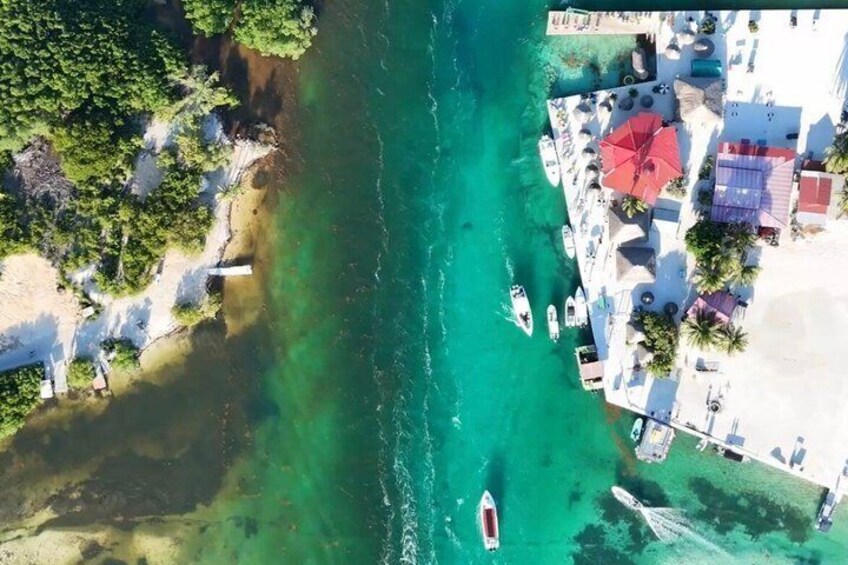 An aerial view of a coastal area with clear turquoise waters, a sandy beach, and several boats. 3