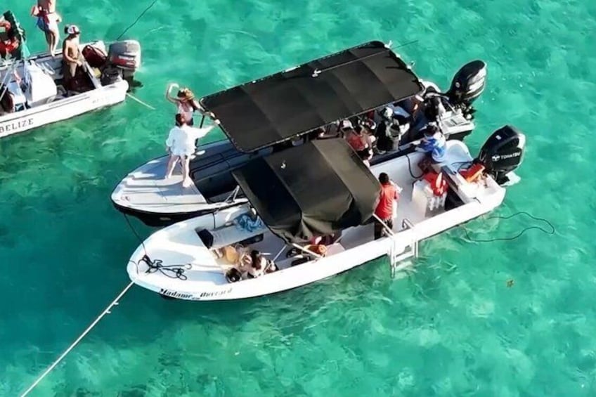 Two boats on turquoise water, one with a covered area and people on board. 4