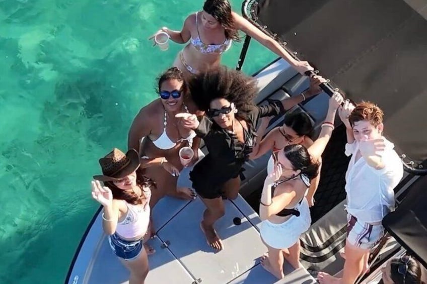 A group of people on a boat with clear turquoise water. 1