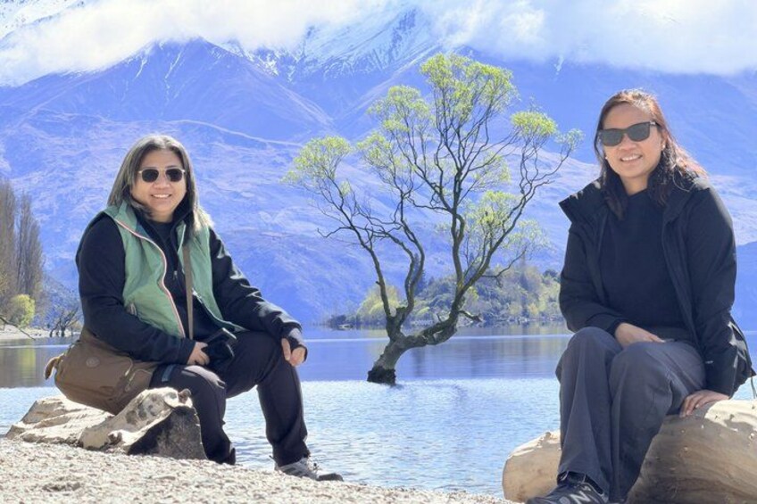 Two people sitting on rocks by a lake with mountains in the background. 5