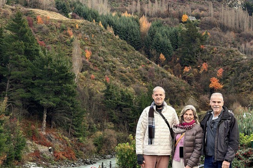 A family of three standing in a mountainous area with autumn foliage. 4