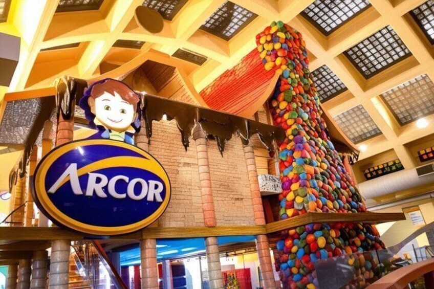 A colorful candy mountain, a cartoon character, and a sign with 'ARCOR' in a mall. 1