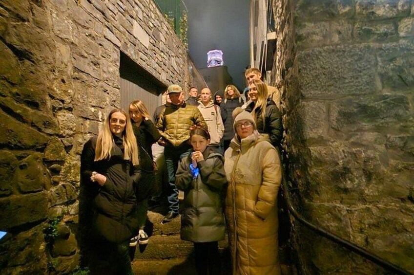 A group of people standing in a stone-walled alleyway. 3