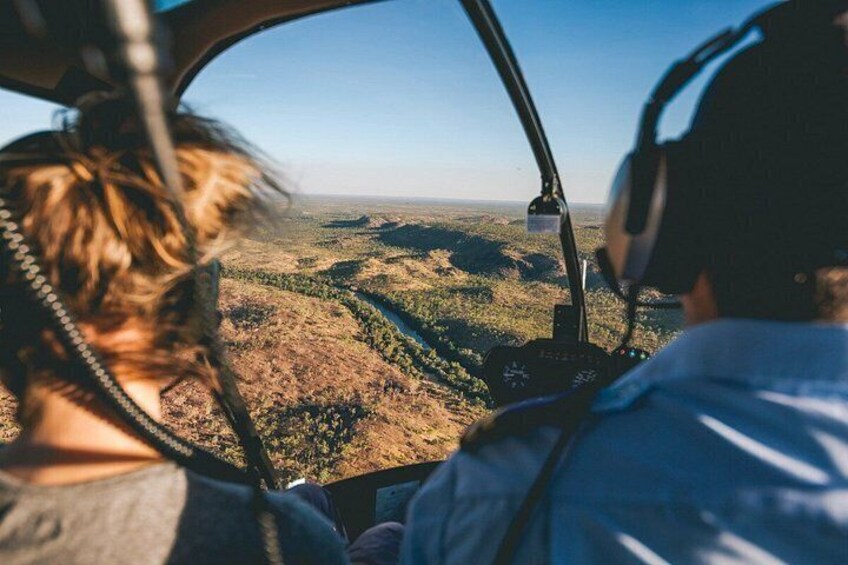 A helicopter cockpit with a view of a forested landscape. 4