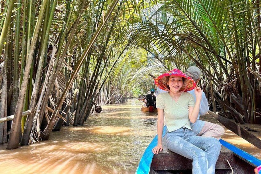 A person sitting on a boat in a waterway surrounded by tall palm trees. 3