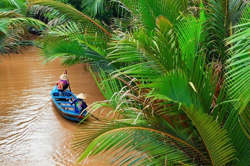A blue boat on a river surrounded by lush green palm trees. 1