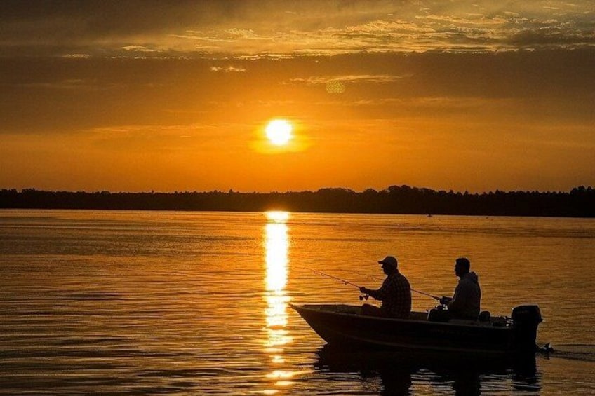 Two people fishing on a boat during sunset. 2
