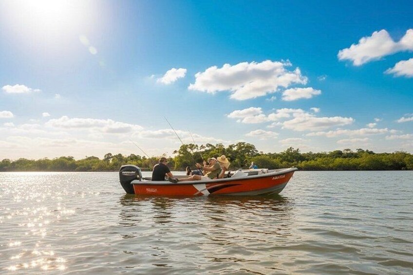 A small motorboat on calm water with a clear sky and trees in the background. 1