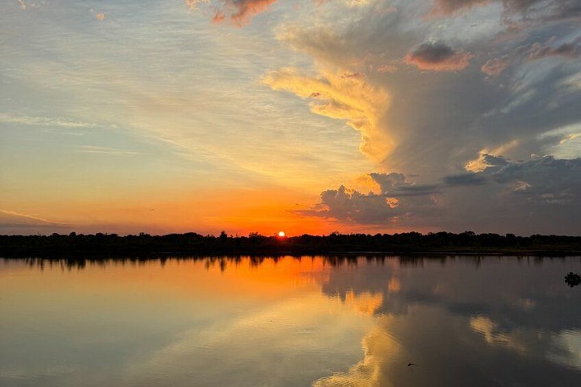 A sunset over a calm lake with a silhouette of trees in the distance. 3