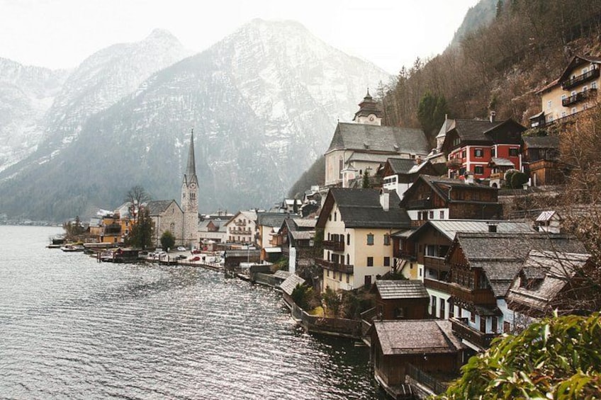 A lakeside village with traditional houses, a church, and snow-capped mountains in the background. 2