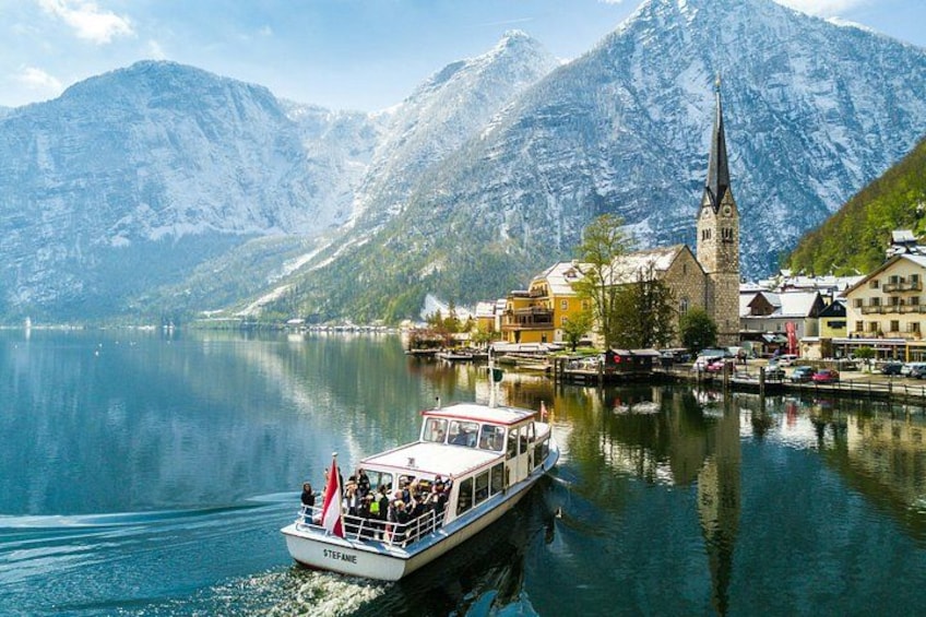 A boat named STEFANE on a calm lake with a church and mountains in the background. 1
