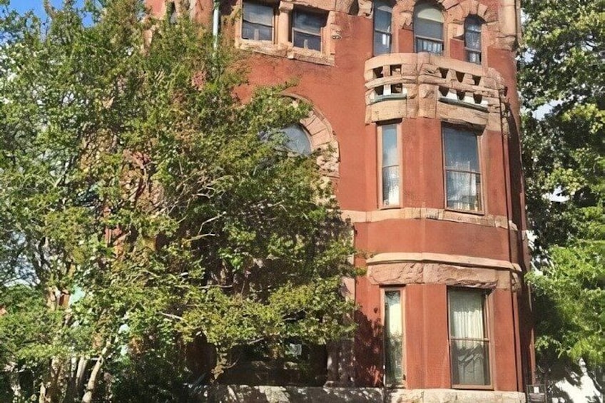 A red brick building with arched windows and a balcony. 3