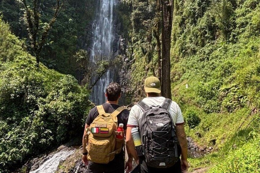 Two people hiking with a waterfall in the background. 3