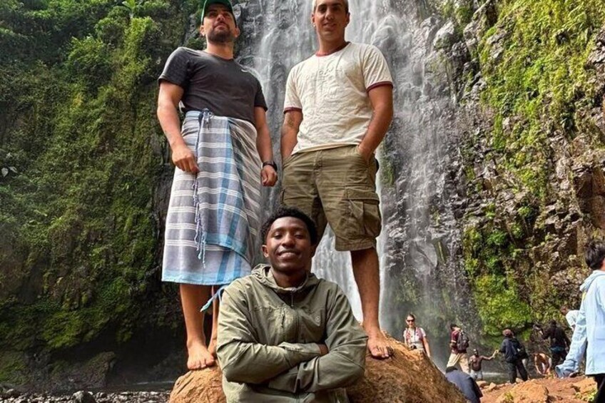 A waterfall, rocky terrain, and people in outdoor attire. 2