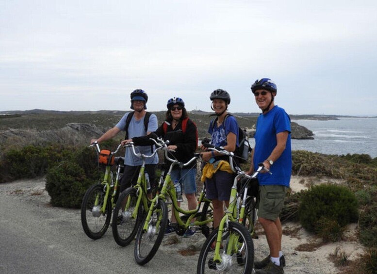Four people on bicycles on a coastal path with a view of the sea. 3