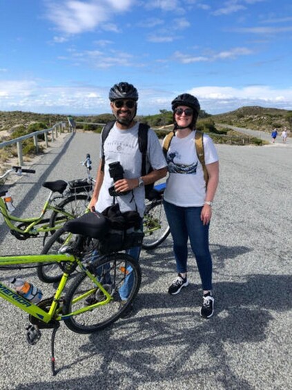 Two people standing next to a green bicycle on a paved path with a clear sky. 5