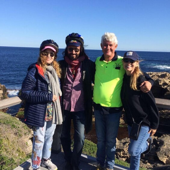 Four people standing on a rocky coastal path with the ocean in the background. 2