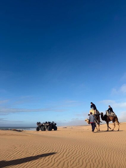 A desert landscape with sand dunes, a clear blue sky, and a quad bike in the foreground. 3