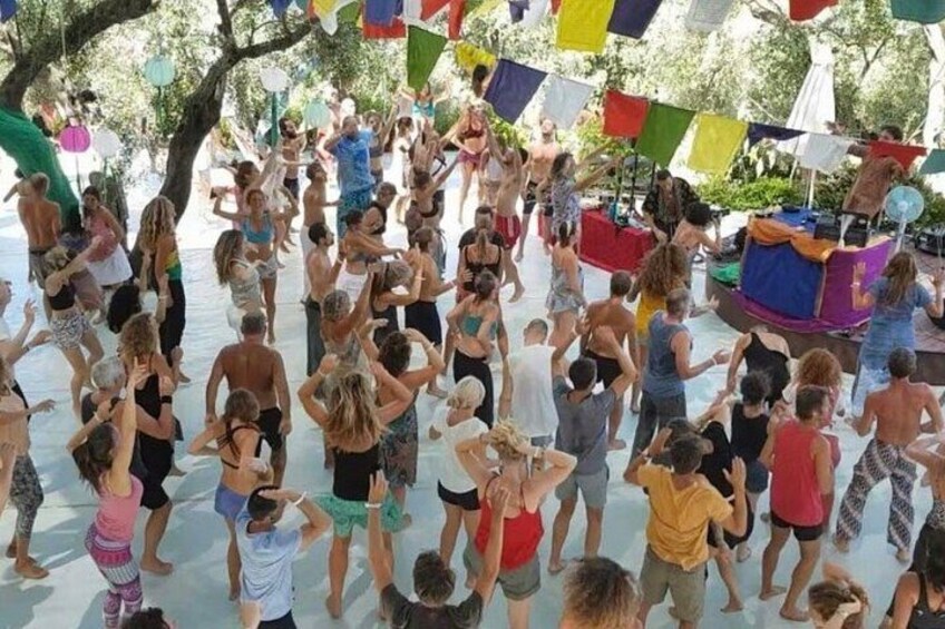 A group of people dancing outdoors under colorful flags. 2